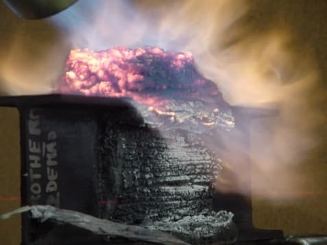 Detalhe da camada intumescida em brasa durante o ensaio de fogo, mostrando a espuma protetora formada sobre o perfil metálico